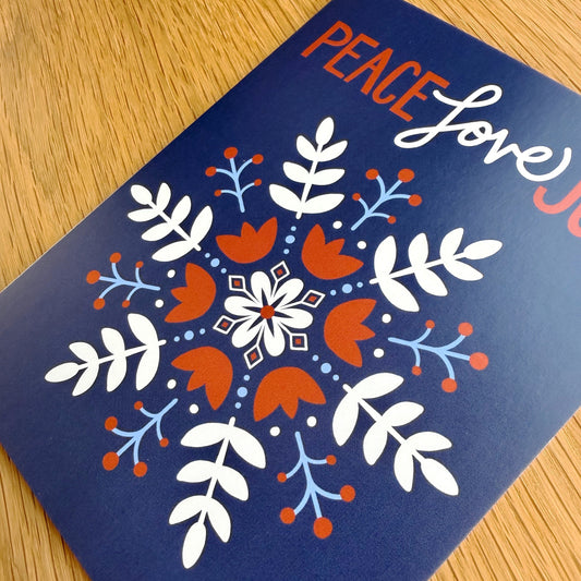 close up angle of Peace Love Joy card - navy blue with Scandinavian snowflake design